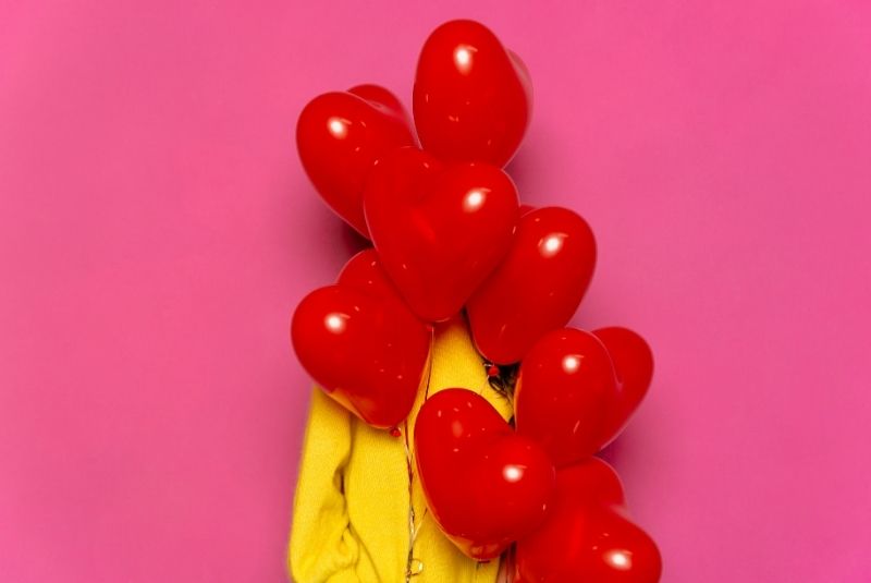 Mujer joven con globos en forma de corazón por San Valentín